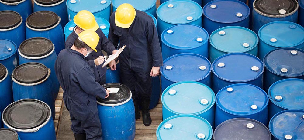 Group of men working at a chemical warehouse classifying barrels
